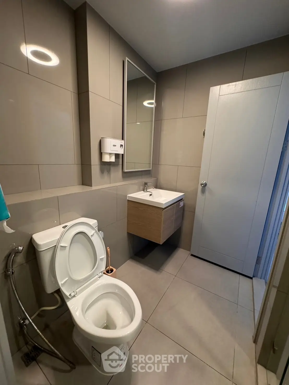 Modern bathroom with sleek fixtures and neutral tiles, featuring a wall-mounted sink and toilet.