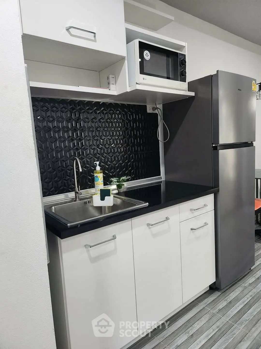 Modern kitchen with sleek black backsplash, stainless steel fridge, and microwave.