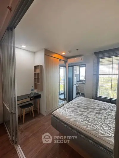 Modern bedroom with balcony view and study area in stylish apartment