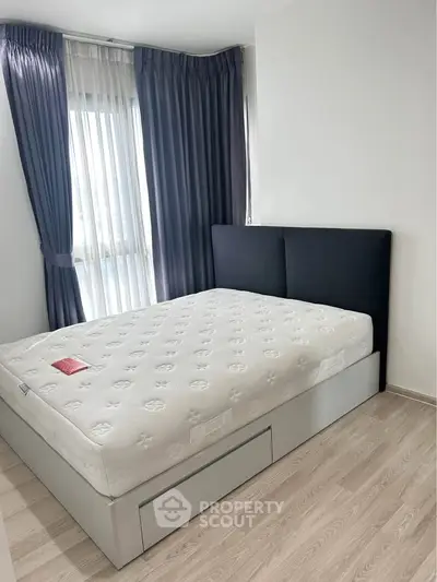 Modern bedroom with stylish bed and floor-to-ceiling windows in a bright apartment.