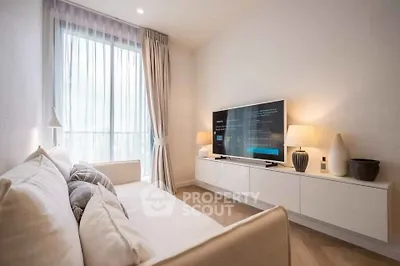 Modern living room with cozy sofa and large TV, featuring elegant decor and natural light.