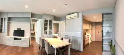 Spacious modern living room with dining area and open kitchen featuring sleek cabinetry and hardwood floors.