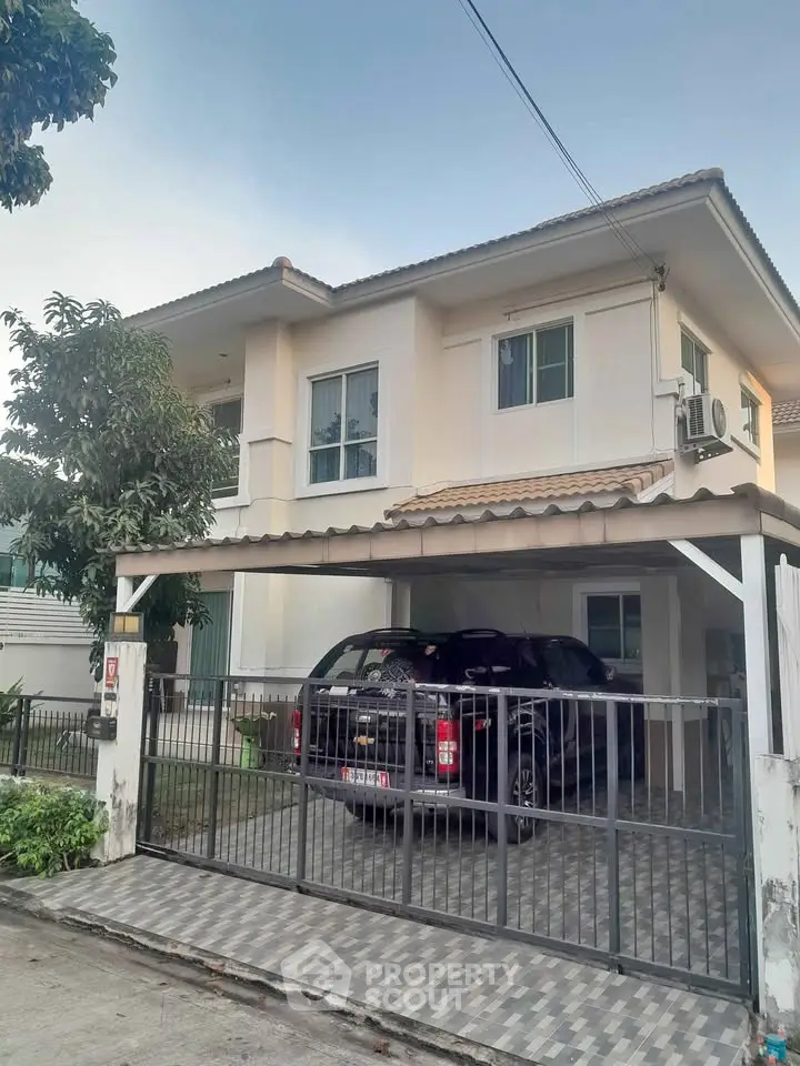 Charming two-story house with carport and lush greenery in a serene neighborhood.