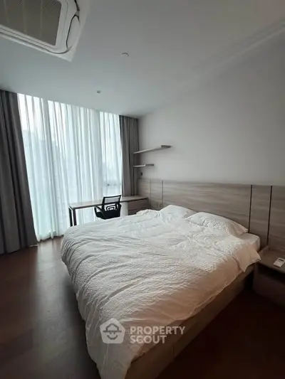 Spacious bedroom with modern furnishings and large window for natural light.