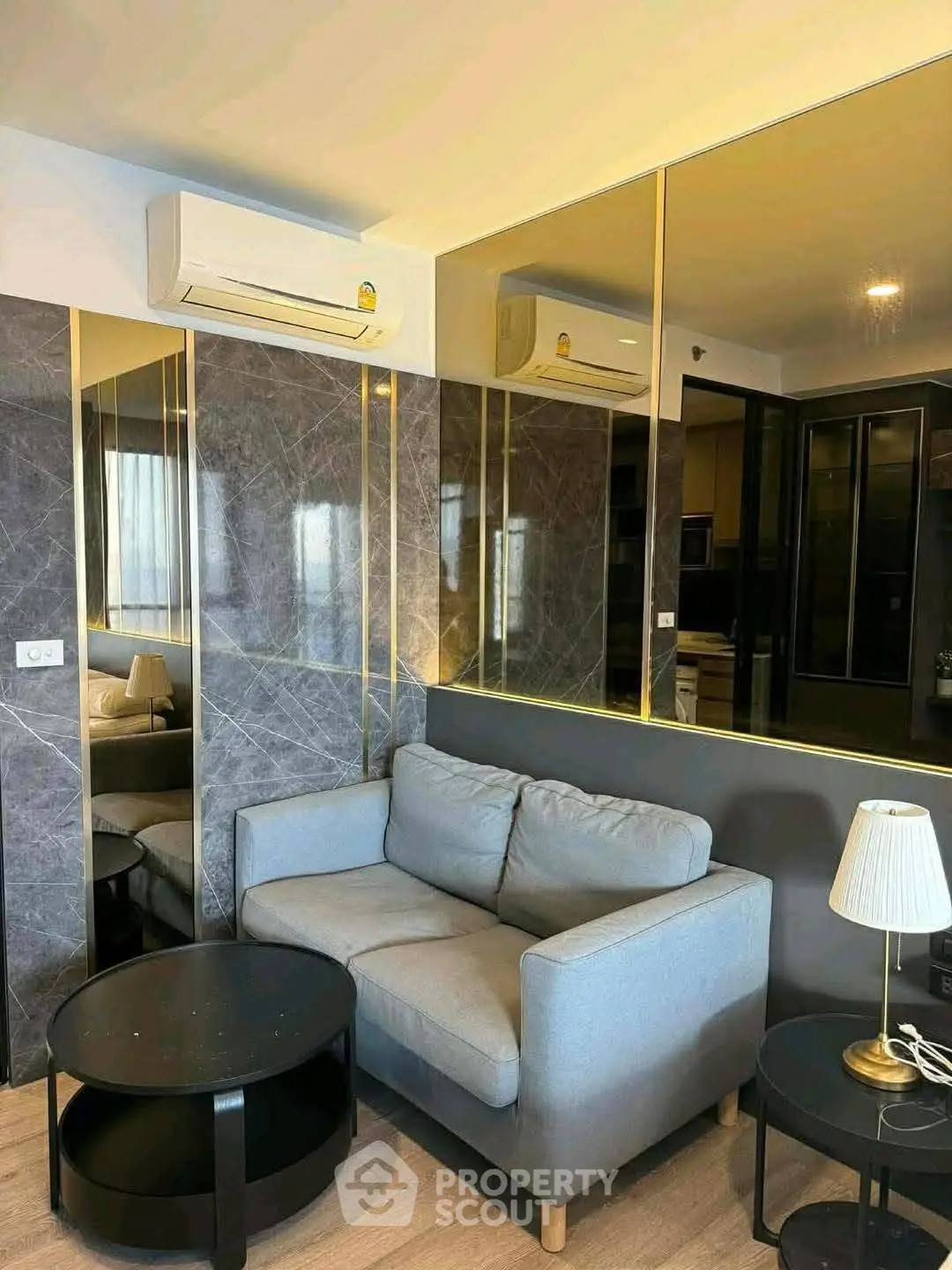 Modern living room with stylish sofa, mirrored walls, and elegant lighting