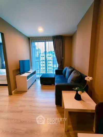 Modern living room with cozy sofa, TV, and city view through large window.