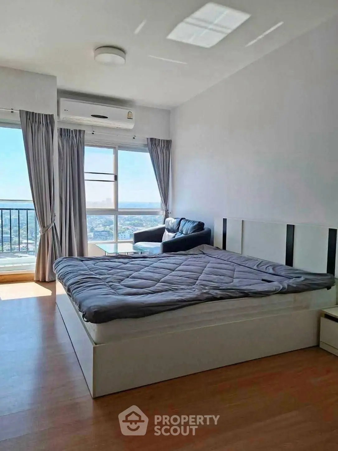 Spacious bedroom with large windows offering stunning city views and abundant natural light.