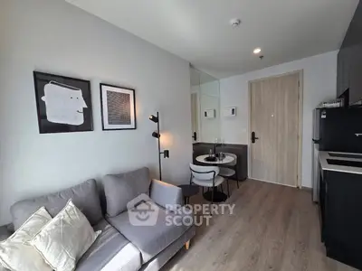 Modern living room with cozy gray sofa, stylish decor, and compact dining area in a chic apartment.