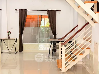 Spacious modern living room with staircase and large window, perfect for natural light.
