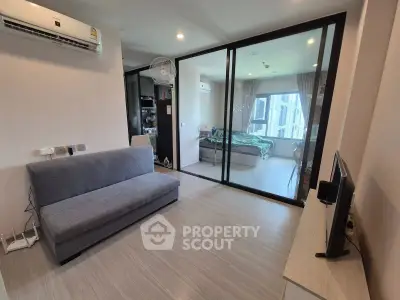 Modern apartment interior with cozy living room and bedroom separated by glass doors, featuring sleek furniture.