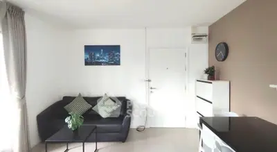 Modern living room with sleek black sofa and stylish decor in a bright apartment.