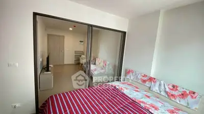 Modern bedroom with floral bedding and sliding glass doors leading to a cozy study area.