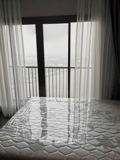 Spacious bedroom with stunning city view through large windows and sheer curtains.