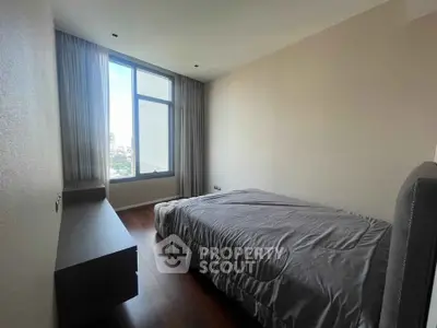 Spacious bedroom with large window offering city views and natural light.