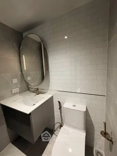 Modern bathroom with sleek design, featuring a round mirror, stylish sink, and contemporary fixtures.