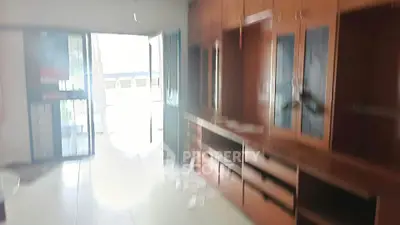 Spacious living room with built-in wooden cabinets and large windows.