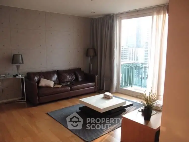 Modern living room with leather sofa, city view balcony, and stylish decor.