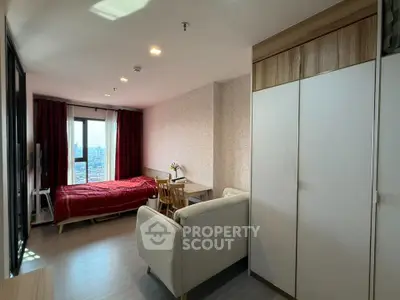 Cozy studio apartment with city view, featuring a comfortable bed, sofa, and workspace.