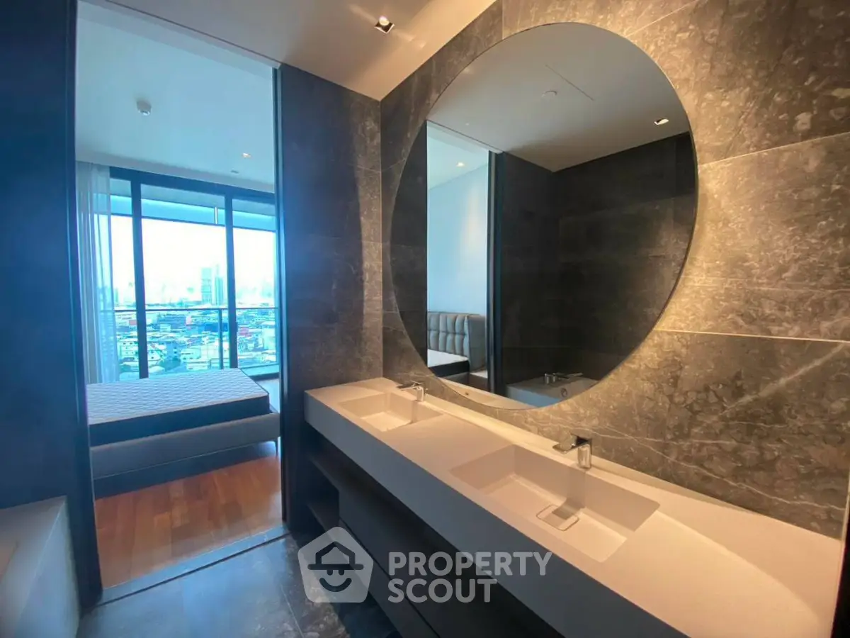 Luxurious modern bathroom with dual sinks and a glimpse of a stylish bedroom with city view.