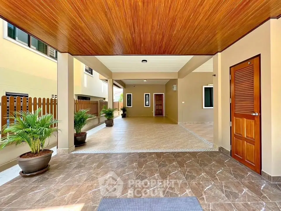 Spacious covered entrance with elegant tile flooring and wooden ceiling in modern property.
