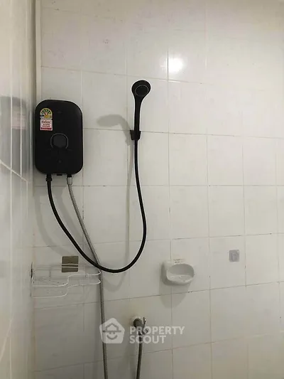 Minimalist bathroom with wall-mounted shower and white tiles, perfect for modern living.