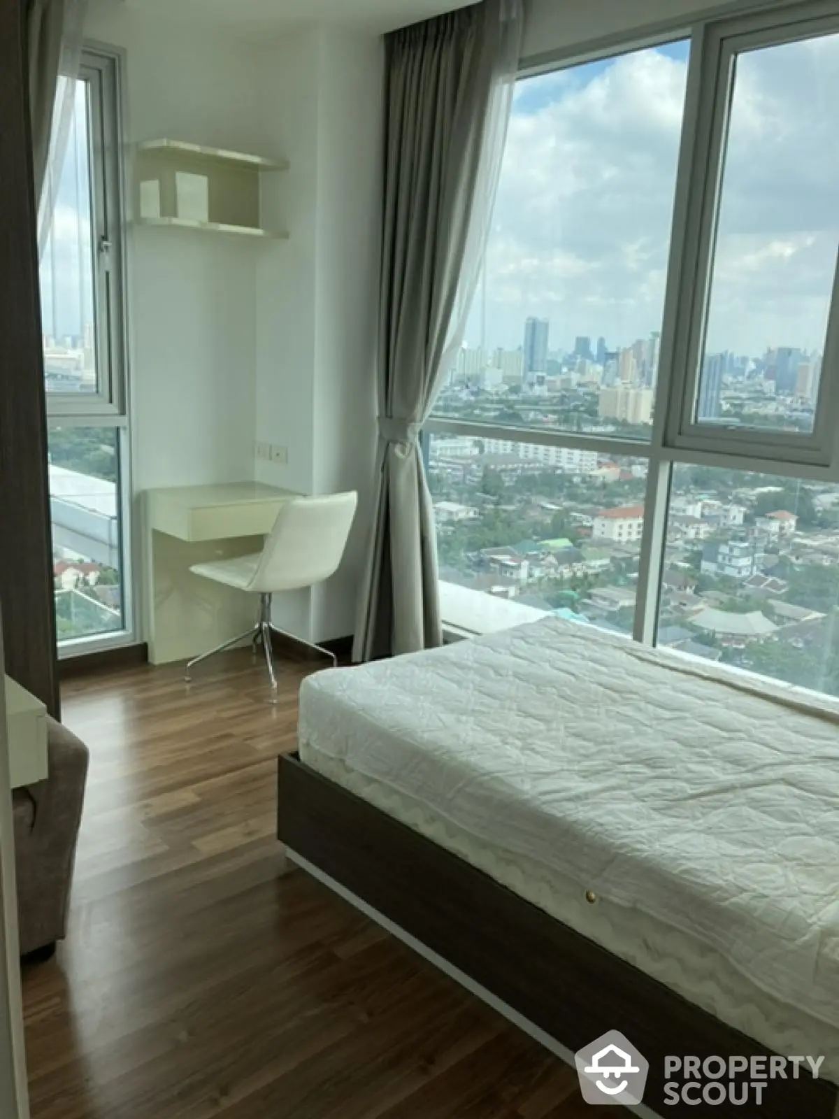 Modern bedroom with city view, featuring large windows and stylish furnishings.