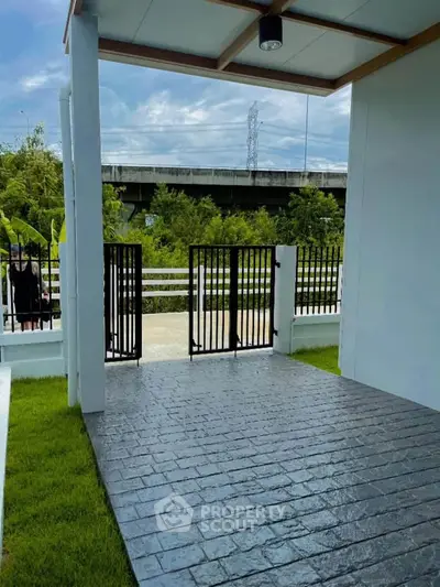 Modern home entrance with sleek gate and lush greenery