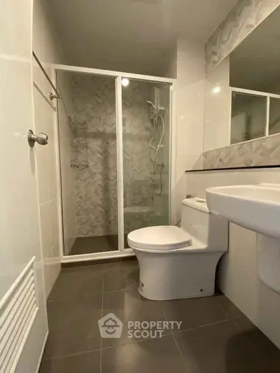Modern bathroom with glass shower and sleek fixtures in contemporary apartment.