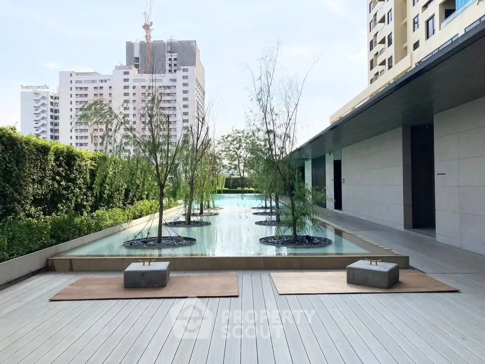 Luxurious modern building exterior with serene water feature and lush greenery