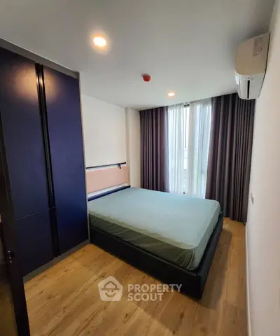 Modern bedroom with large window and minimalist design, featuring a comfortable bed and sleek wooden flooring.