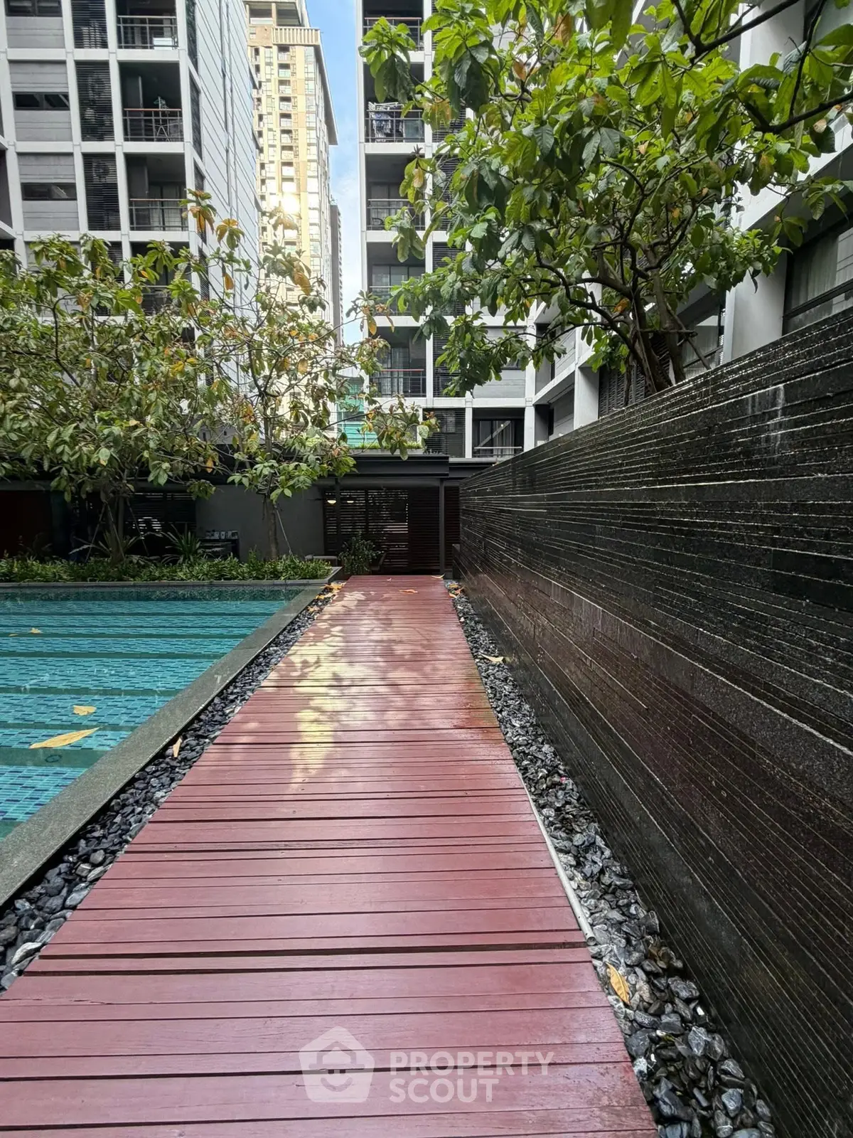 Modern apartment complex with poolside walkway and lush greenery