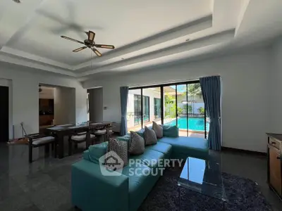 Spacious living room with pool view, modern furniture, and elegant ceiling fan in luxury home.