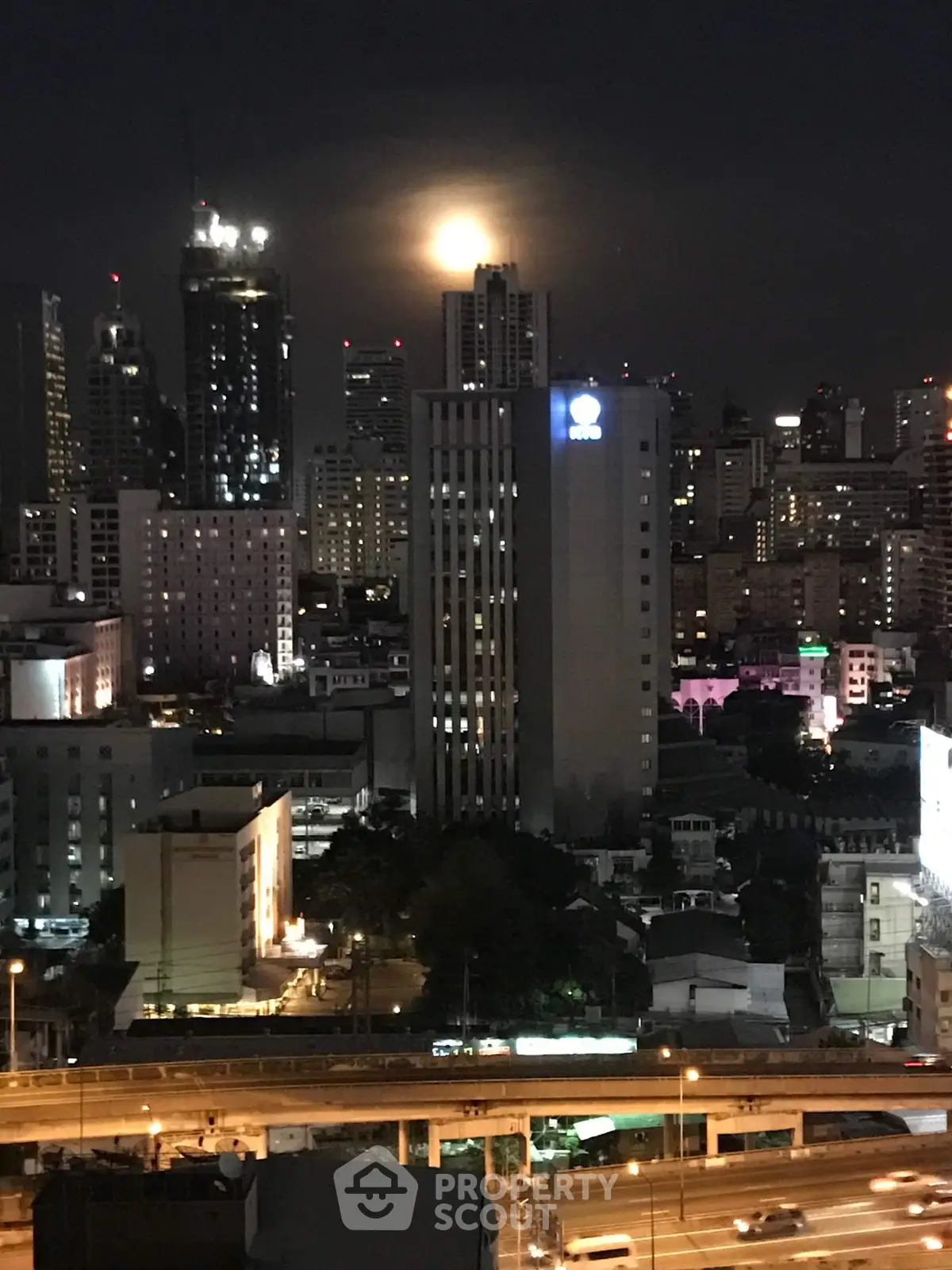 Stunning cityscape view with illuminated skyscrapers and moonlit sky, perfect for urban living enthusiasts.