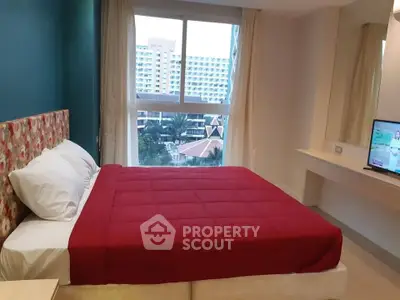 Modern bedroom with vibrant red bedding and city view from window