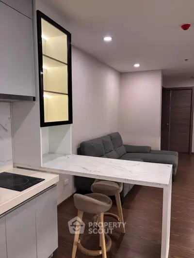 Modern apartment interior with sleek kitchen and cozy living area featuring stylish furniture.