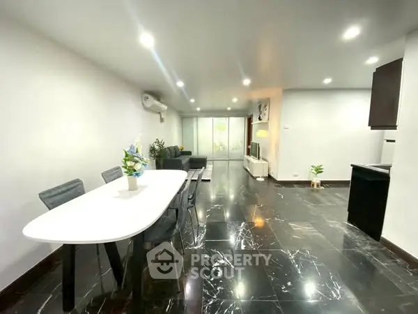 Spacious modern living room with elegant dining area and sleek marble flooring.