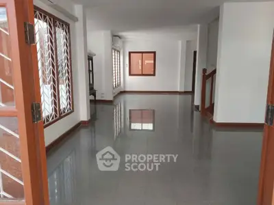 Spacious open-plan living area with large windows and glossy tiled floors