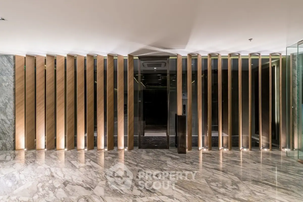Luxurious modern elevator lobby with marble flooring and elegant wooden paneling.