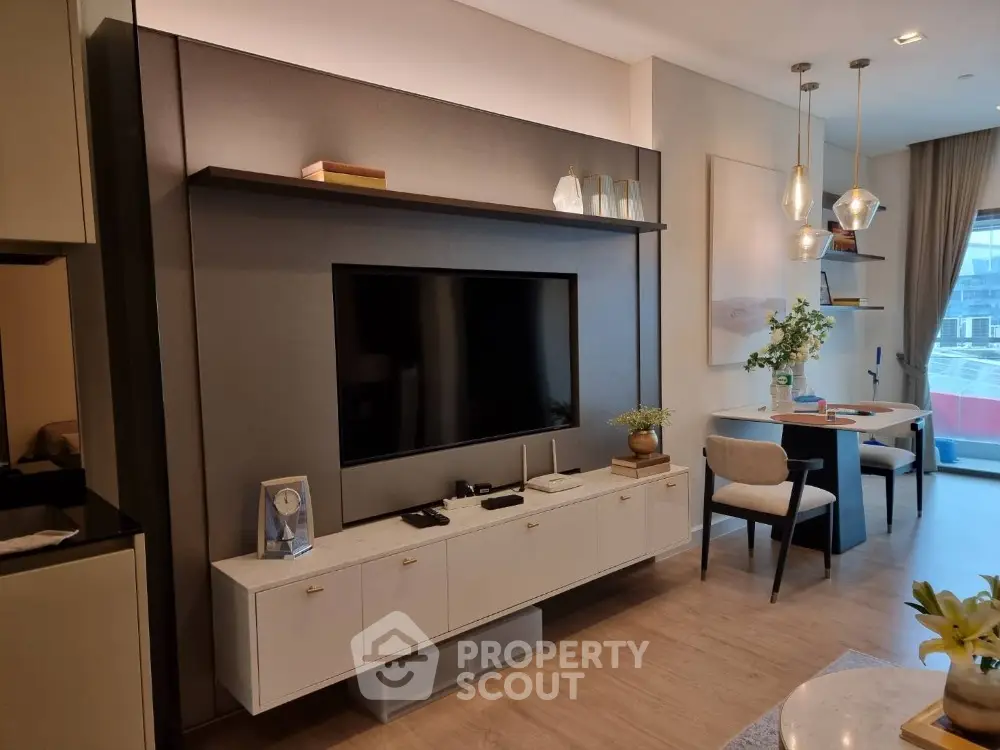 Elegant living room with modern entertainment wall unit, chic pendant lighting, and a cozy dining area, showcasing a blend of style and comfort.