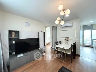 Modern living room with stylish decor and dining area, featuring a sleek TV unit and elegant lighting.