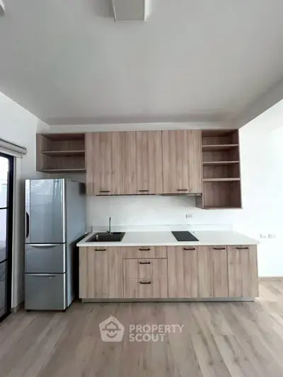 Modern kitchen with sleek cabinetry and stainless steel fridge in a stylish apartment.