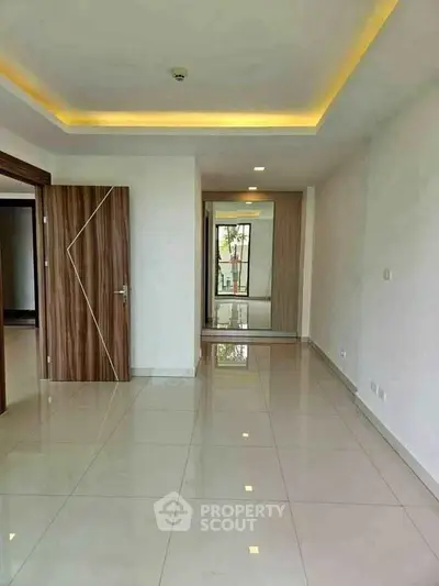 Spacious modern living room with glossy tiled floors and stylish wooden door.