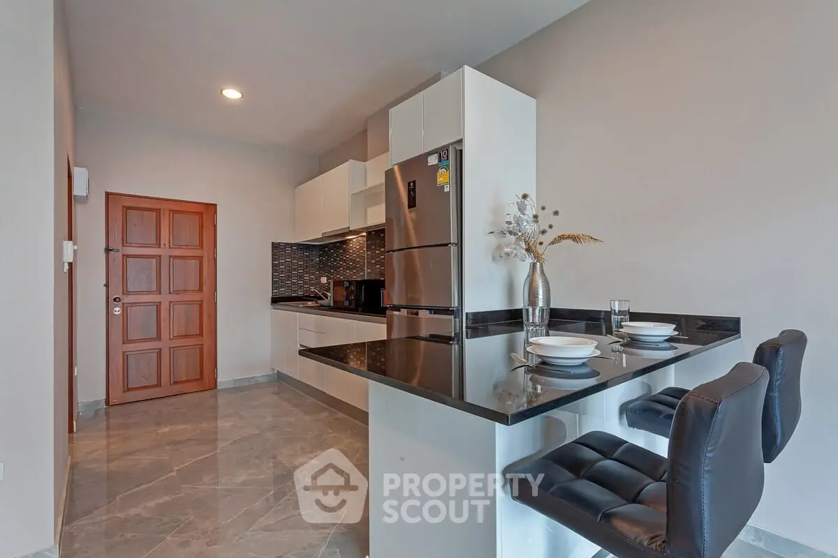 Modern kitchen with sleek design, featuring a breakfast bar and stainless steel appliances.