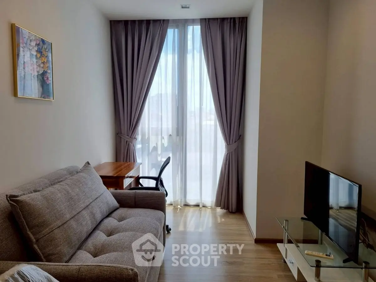 Cozy living room with modern sofa, desk, and large window with curtains