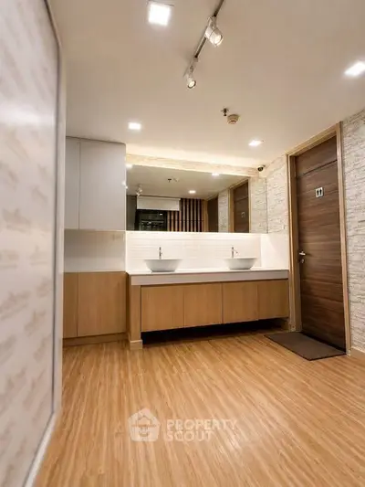 Modern bathroom with dual sinks and wooden accents in a stylish real estate property.