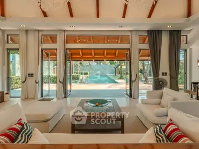 Luxurious living room with pool view, high ceilings, and elegant decor in a modern villa.