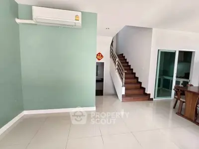 Spacious modern living room with staircase and air conditioning, ideal for family gatherings.