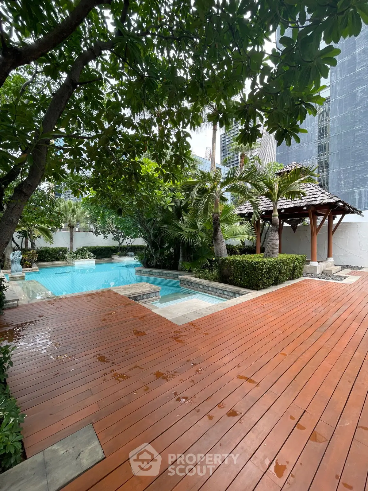 Luxurious backyard with wooden deck and private pool surrounded by lush greenery.