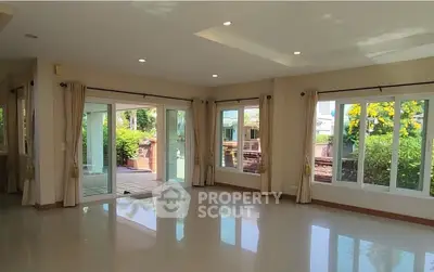 Spacious living room with large windows and garden view, perfect for natural light lovers.