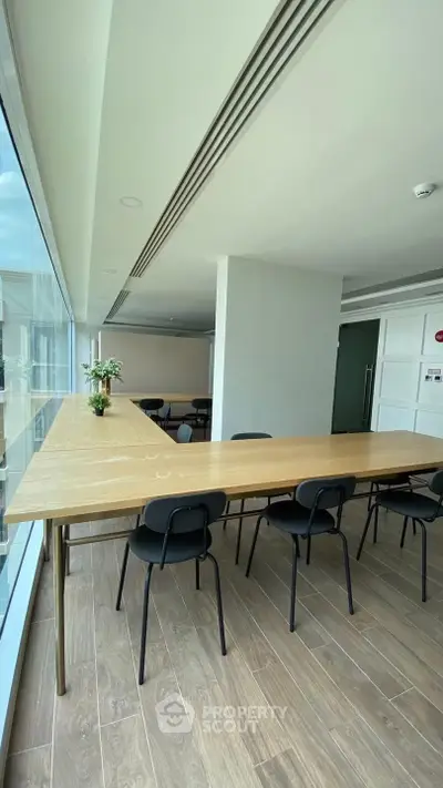 Modern study area with large windows and wooden table, ideal for collaborative work.